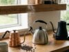 Coffee Kettles 101: Choosing the Right Gooseneck Kettle for Precision Pouring _A barista pouring hot water from a variable temperature electric gooseneck kettle into a pour-over dripper, demonstrating precise flow control and even saturation of coffee grounds.