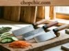 Best Nakiri Knives: Why the Japanese Vegetable Cleaver Should Be Your Next Purchase _A Japanese Nakiri knife with a rectangular blade chopping through a stack of carrots on a wooden board, demonstrating the vertical push-cut technique that ensures full contact with the surface.