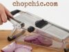 No More Tears: Testing the Best Manual Onion Slicers _A side-by-side comparison of the QPEY onion holder with stainless steel prongs versus an adjustable mandoline slicer, demonstrating the different methods for securing the onion to prevent eye irritation and finger cuts.