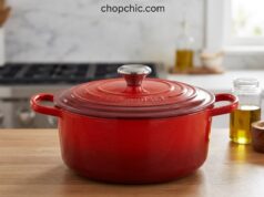 Le Creuset Dutch Oven Review: Why Bakers Pay a Premium A vibrant Cerise red Le Creuset Signature enameled cast iron Dutch oven sitting on a wooden cutting board, with its tight-fitting lid resting beside it to reveal a deeply browned, crusty sourdough boule resting inside the pristine light-sand interior.