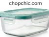 OXO Good Grips Smart Seal Glass Container Review: The Workhorse of Food Storage A close-up view of a clear OXO Smart Seal Glass container filled with meal-prepped food, with its lid resting alongside to display the four heavy-duty plastic locking tabs and the removable silicone gasket.