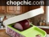 Vidalia Chop Wizard Review: The Onion Chopper That’s Been Around Since the ’90s A classic green and clear plastic Vidalia Chop Wizard resting on a kitchen counter, showing a user applying downward force with both hands on the top lid to push a halved white onion through the stainless steel dicing grid into the catch tray below.