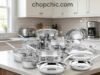Cuisinart 17-Piece Stainless Steel Cookware Set Review A comprehensive 17-piece Cuisinart stainless steel cookware set arranged systematically on a kitchen island, prominently displaying its polished exterior finish, tempered glass lids, and the thick, encapsulated aluminum-core base of an overturned frying pan.