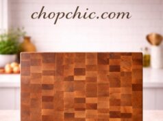 John Boos CCB Series Review: Heavyweight Cutting Board A massive, 2.25-inch thick John Boos CCB Series end-grain chopping block securely positioned on a stainless steel prep station, showcasing its iconic checkerboard wood pattern and heavy, immovable profile beneath a professional butcher's cleaver.