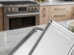 Wildone Stainless Steel Baking Sheet Review: The End of Peeling Coatings? A close-up photograph of a gleaming, uncoated Wildone 18/0 stainless steel baking sheet on a clean kitchen counter, featuring a golden-brown roasted chicken surrounded by vibrant, caramelized root vegetables, showcasing the metallic texture and heat distribution of the raw metal.